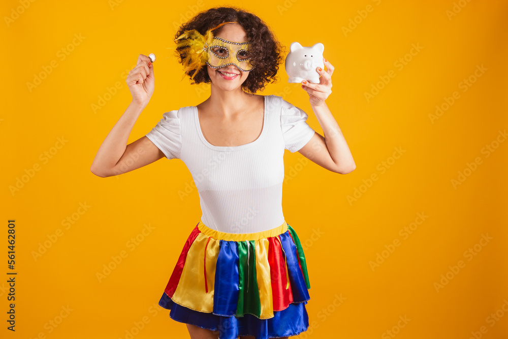 Stockfoto med beskrivningen Beautiful Brazilian woman, dressed in carnival  clothes, colorful skirt and white shirt. wearing mascara, holding piggy  bank and coin. | Adobe Stock