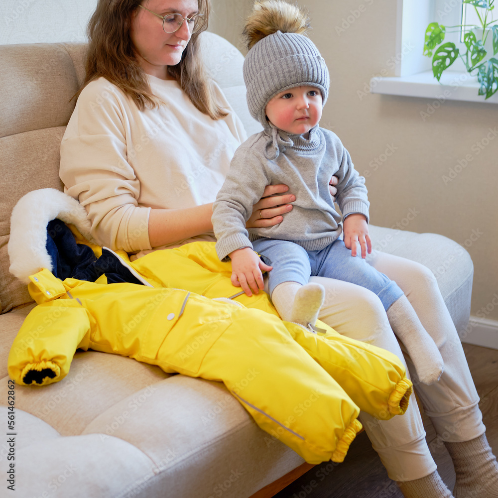 Child is dressed in warm winter clothes for a walk outside. Woman