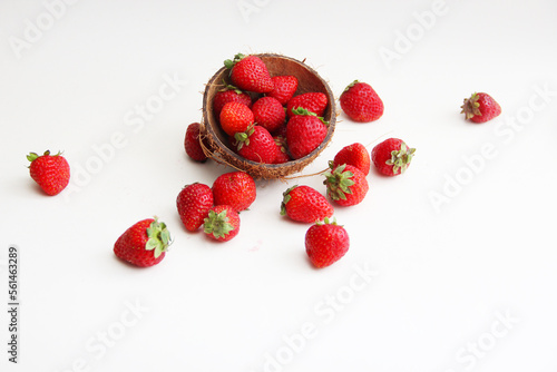 Strawberries in coconut peel. Juicy, red strawberries in a coconut plate on a white background