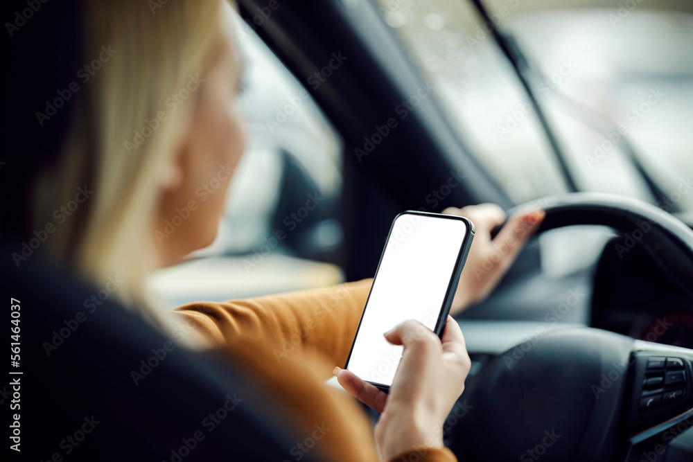 Back view of a woman driving her car with phone in her hands.