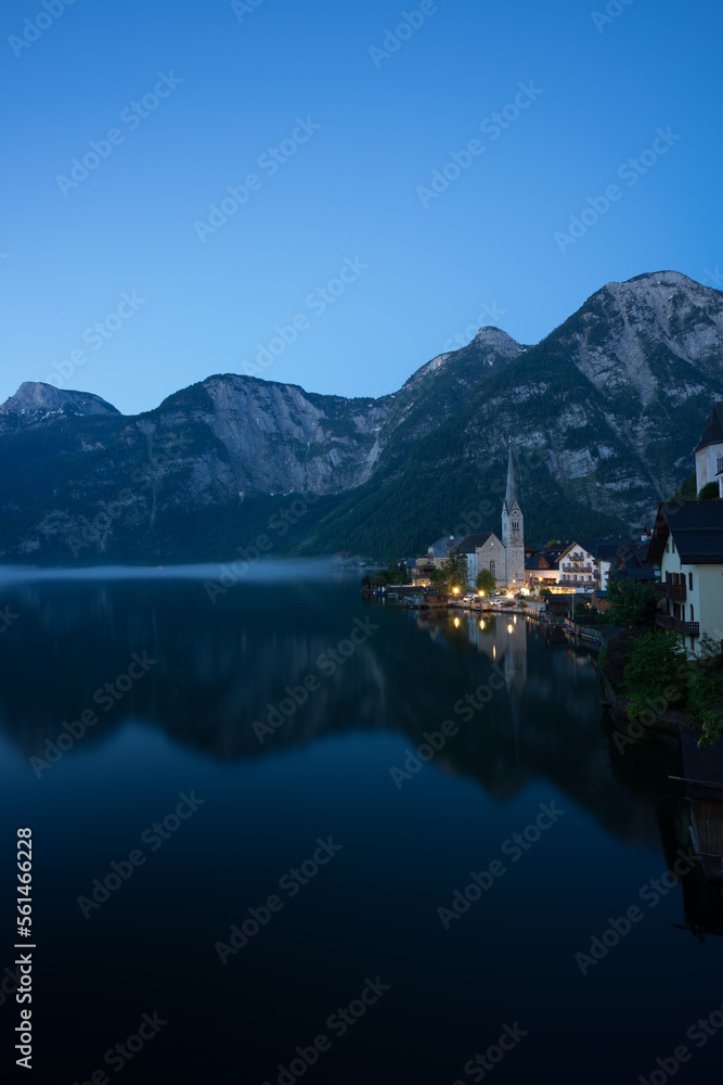 Hallstätter See in Österreich mit beleuchteter Kirche zur blauen Stunde.