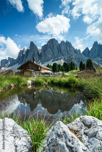 Spiegelung einer Alm in den Dolomiten in Südtirol mit Bergmassiv im Hintergrund.