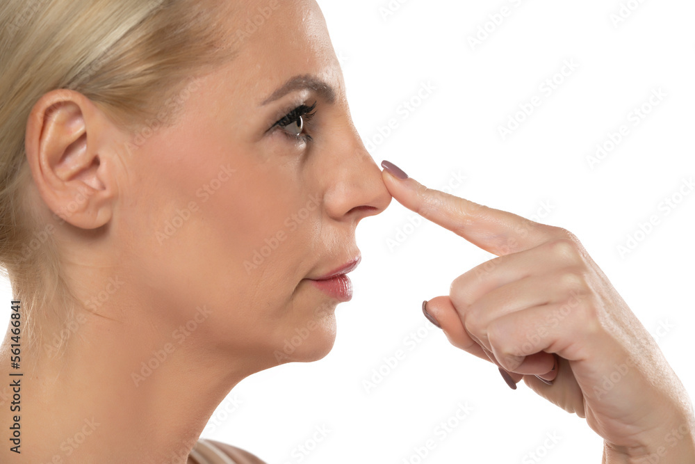Profile od a middle aged serious woman touchinf her nose on a white background Profile od a middle aged serious woman touchinf her nose on a white background