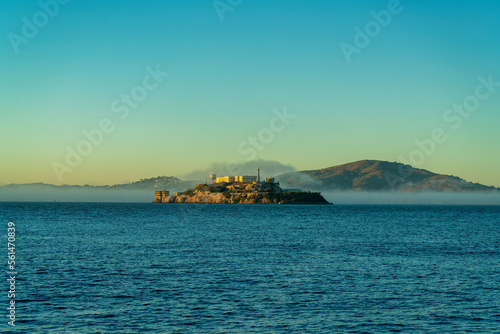 Distant alcatraz insland on the ocean with mist and fog and background mountains in golden sunset or sunrise © Aaron