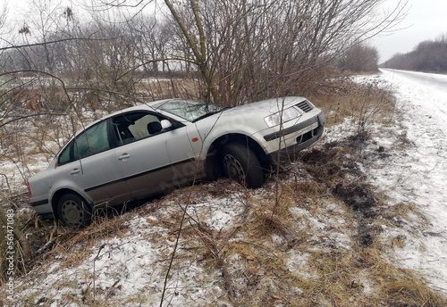 Car in a ditch. Slippery road. Winter accident. Car accident in winter. An abandoned car in a ditch after a traffic accident. Dangerous winter conditions with ice, snow and jerk photo