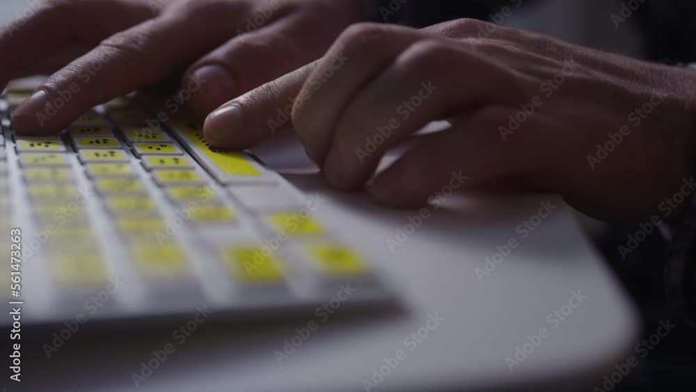 Close-up: A man uses a keyboard with braille.A blind man is typing words on the buttons with her hands. Technological device for visually impaired people. Tactilely touches bumps on the keys
