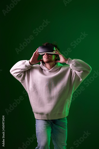 man in vr glasses and sweatshirt plays on blue background. © producer