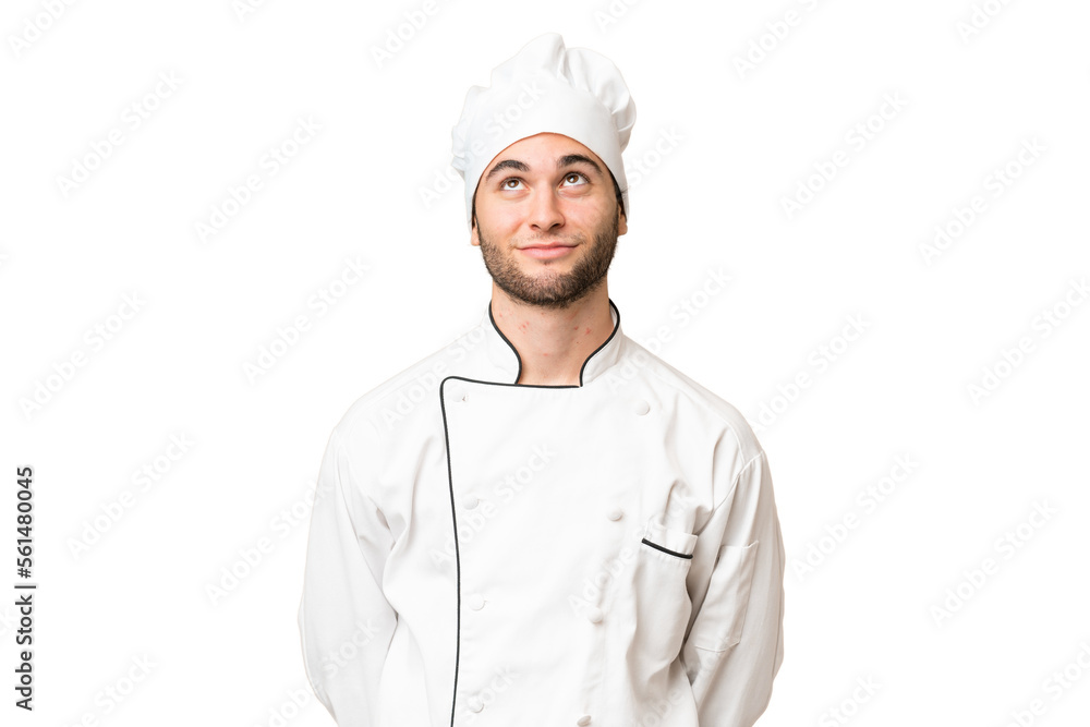 Young handsome chef man over isolated background and looking up