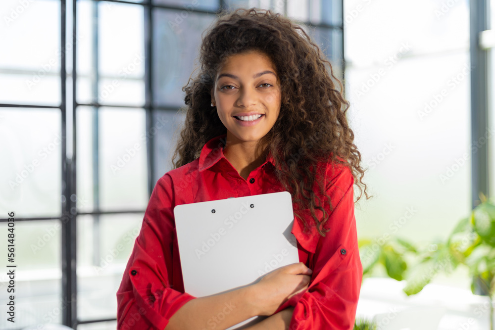 Businesswoman in red shirt standing in the office corridor with documents. Businesswoman in red shirt standing in the office corridor with documents.
