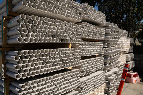 A stack of white PVC conduit pipes for plumbing and electrical construction work.