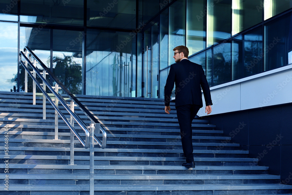 Stylish successful businessman goes up the stairs of the office ...