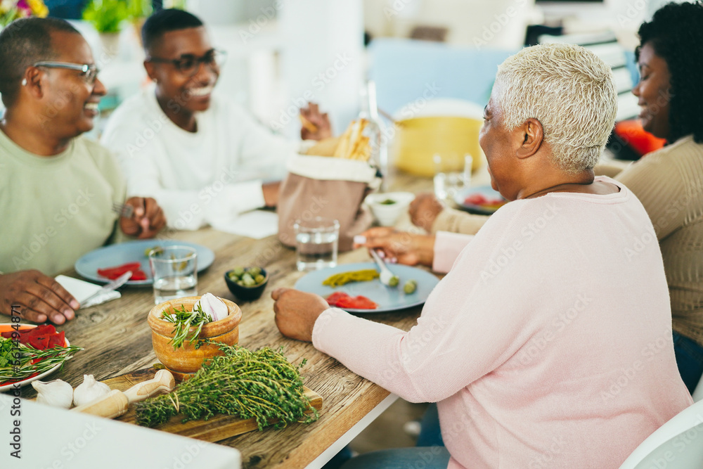 Happy african family eating lunch together at home - Focus on mother head Happy african family eating lunch together at home - Focus on mother head