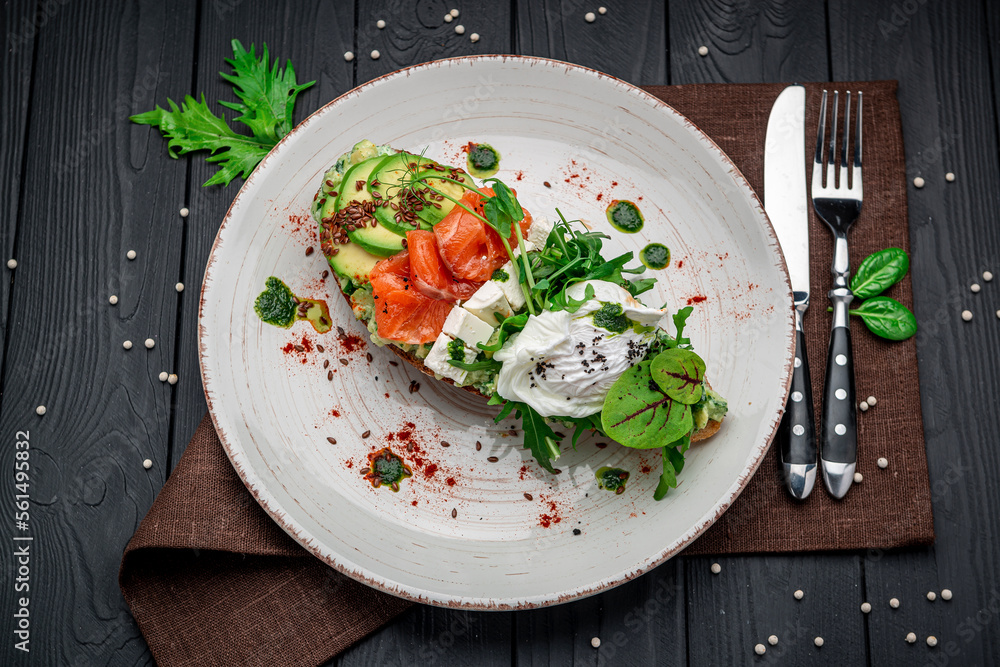 Bruschetta with sliced avocado, feta cheese, pesto sauce, poached egg and salted salmon.