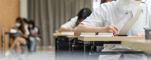 Exam at school with student's taking educational admission test in class, thinking hard, writing answer in university classroom, education and world literacy day concept