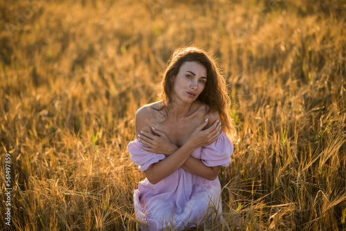 portrait of a happy young girl in a dress in a wheat field at sunset, the concept of peace and unity with nature