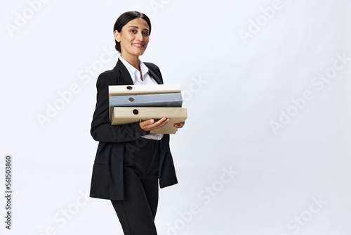 Business woman with a folder of documents in her hands in a black business suit and glasses shows signals gestures and emotions on a white background, work freelancer online training