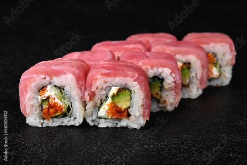 Tuna sushi roll with caviar on black concrete background