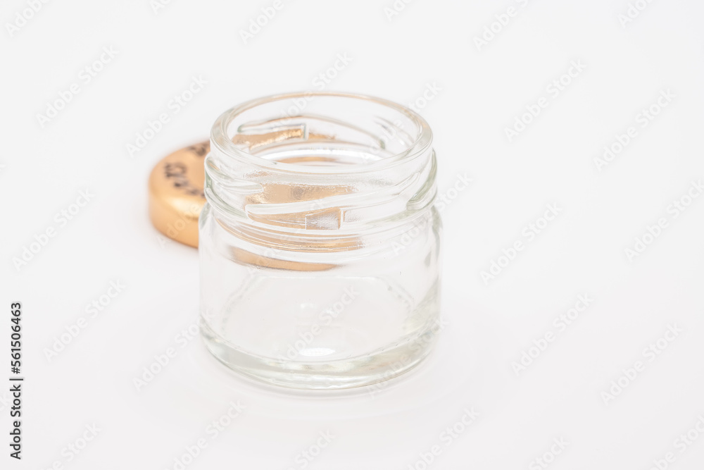close up of a small empty clear glass jar with a bronze coloured screw down metal lid close up of a small empty clear glass jar with a bronze coloured screw down metal lid