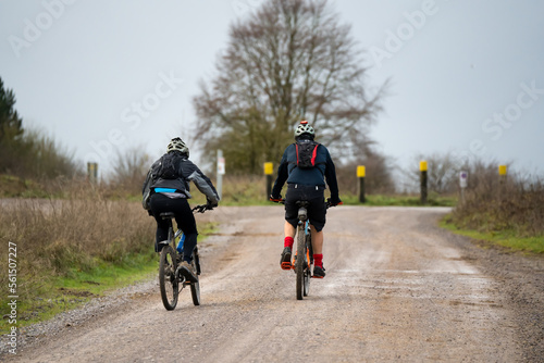 Fototapeta Naklejka Na Ścianę i Meble -  a pair of casual cyclists riding along across a country mud track