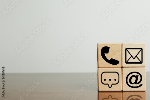 A set of contact icons (phone, email, mail, letter) arranged on wooden cubes on white background with copyspace use for communication, contact information, and business idea.