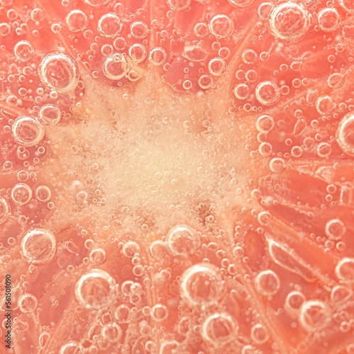 Slice of grapefruit in sparkling water. Grapefruit slice covered by bubbles in carbonated water. Grapefruit slice in water with bubbles