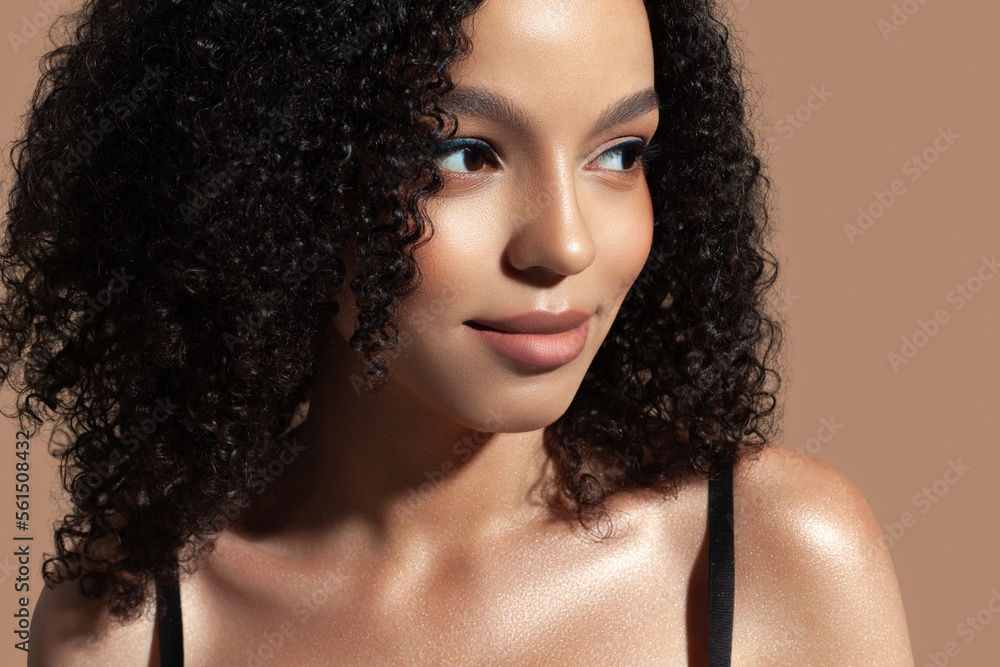 Beautiful young woman on beige background. Natural makeup, glowing dark skin Beautiful young woman on beige background. Natural makeup, glowing dark skin