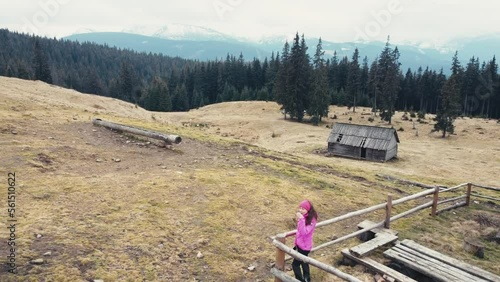 A girl drinks coffee near huts in the mountains. Polonyna Kukul. Drone view. Ukraine photo