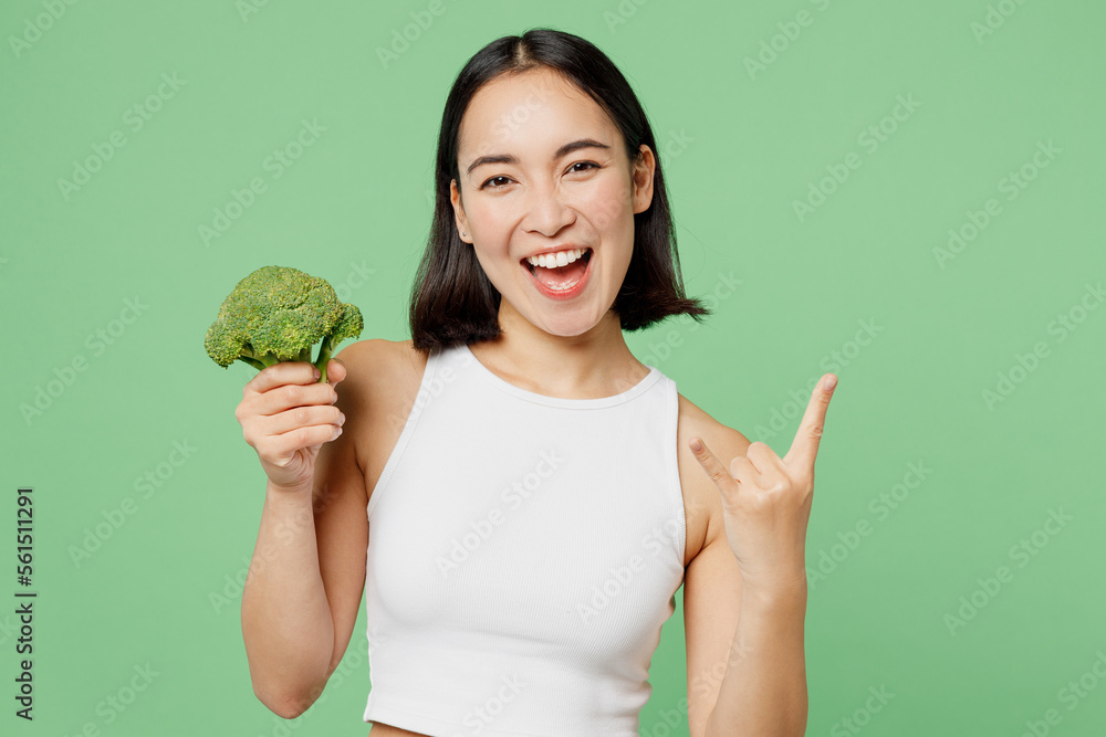 Young woman wears white clothes hold in hand broccoli vegetable showing