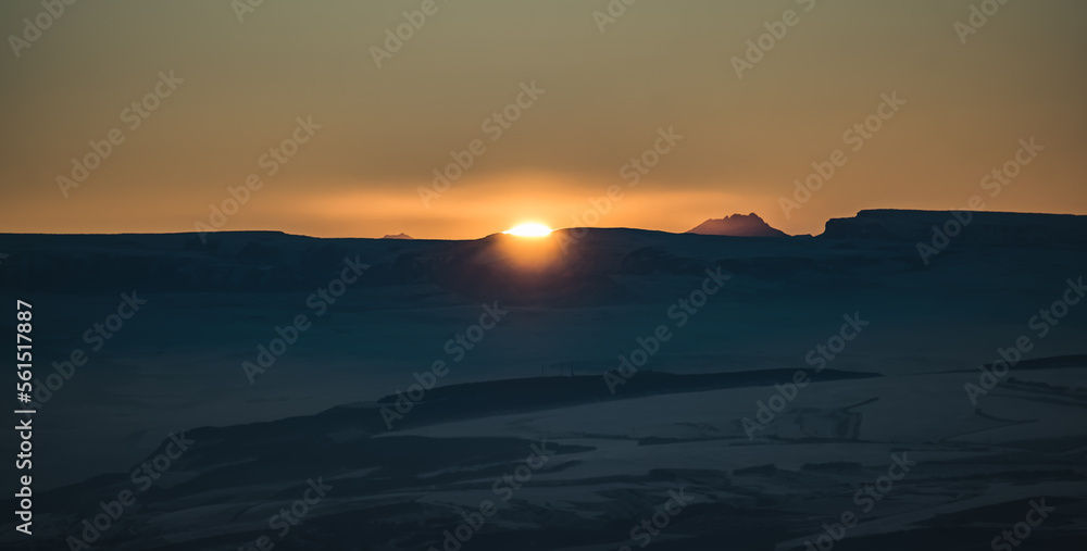 Panorama of the mountain range of the Caucasus Mountains at sunset, view of the mountain peaks in winter in the evening at sunset