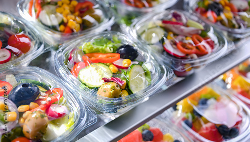 Boxes with pre-packaged vegetable salads in a commercial fridge