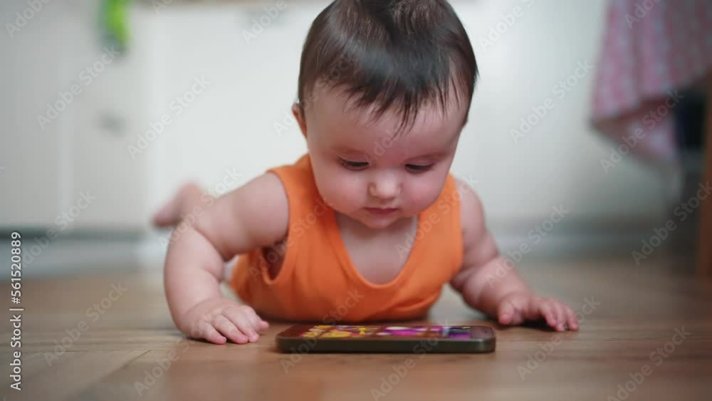 Baby play smartphone on lies on the floor. Happy family a dream kid concept. little baby looks in surprise at the smartphone. lifestyle baby girl studying smartphone Baby play smartphone on lies on the floor. Happy family a dream kid concept. little baby looks in surprise at the smartphone. lifestyle baby girl studying smartphone