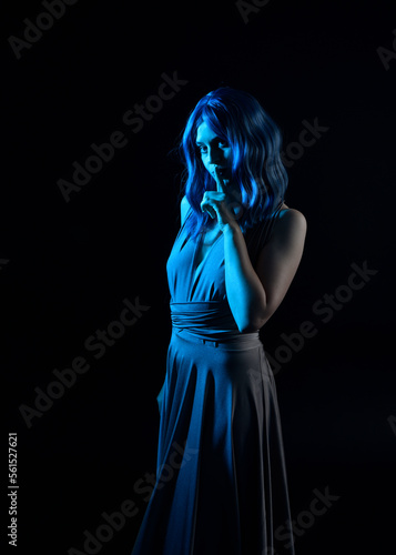  close up portrait of pretty girl with blue hair wig & elegant gown with expressive facial expressions & gestural arm poses. colourful neon gel lighting, isolated on studio background.