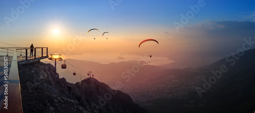Leisure and skydiving from the Babadag mountain over the Fethiye resort  Turkey. Panoramic landscape with silhouettes of parasailing touristers flying near the top station of Oludeniz cable car.