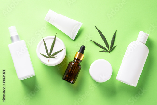 Cannabis cosmetic products. Cream, soap, serum bottle and others. Flat lay image on green background.