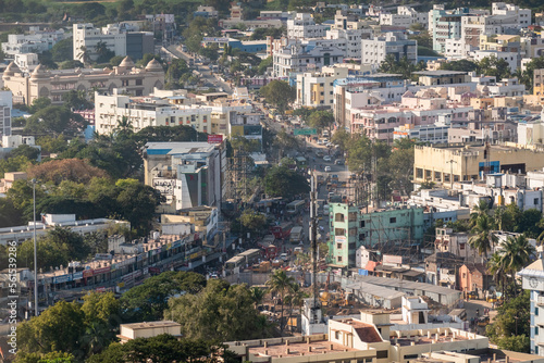 Aerial cityscape of a road passing through a crowded neighbourhood in the town of Tiruchirappalli.