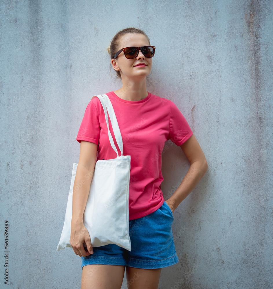 Female model wearing pink blank t-shirt on the background of an gray wall. Female model wearing pink blank t-shirt on the background of an gray wall.