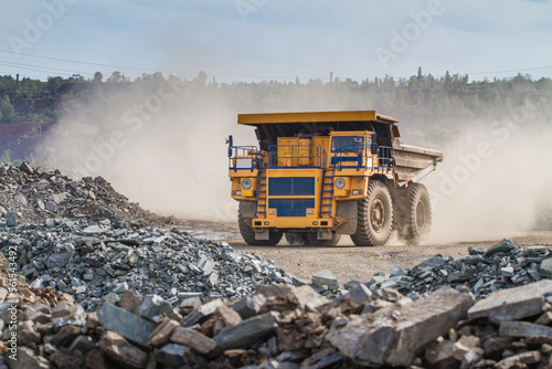 Large dump truck for removal of rock mass from the quarry for open-pit mining of minerals. Initial stage of melalurgy, machinery for the extraction of raw ore.