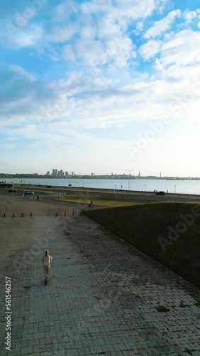 Vertical video: A person rides a scooter near the beach overlooking the city