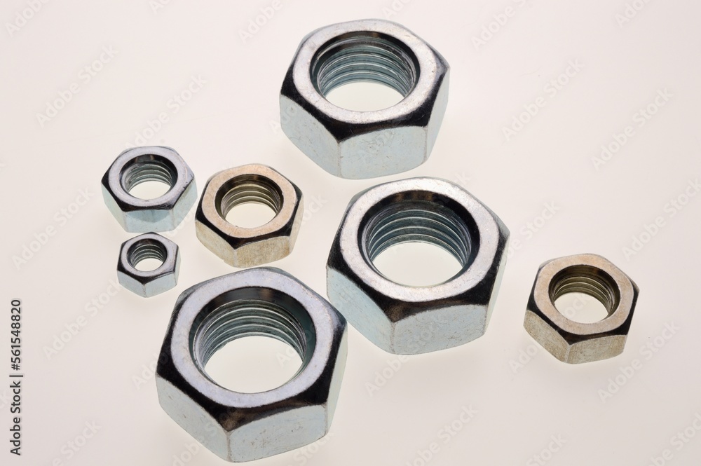 New, chrome-plated bolts and nuts of different sizes lie on a white background. Close-up New, chrome-plated bolts and nuts of different sizes lie on a white background. Close-up