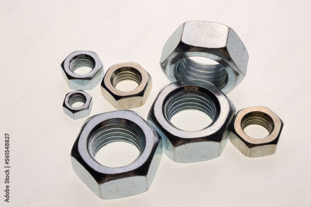 New, chrome-plated bolts and nuts of different sizes lie on a white background. Close-up New, chrome-plated bolts and nuts of different sizes lie on a white background. Close-up