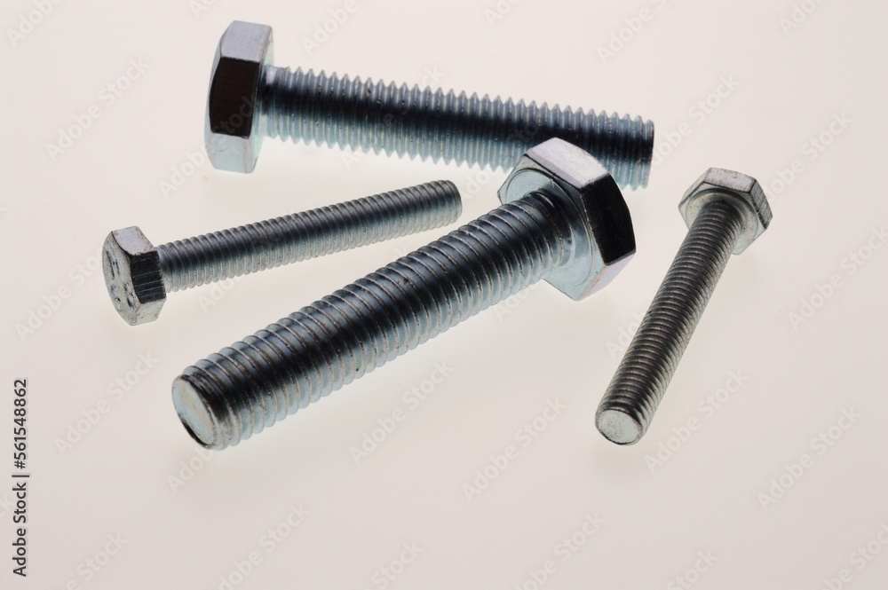 New, chrome-plated bolts and nuts of different sizes lie on a white background. Close-up New, chrome-plated bolts and nuts of different sizes lie on a white background. Close-up