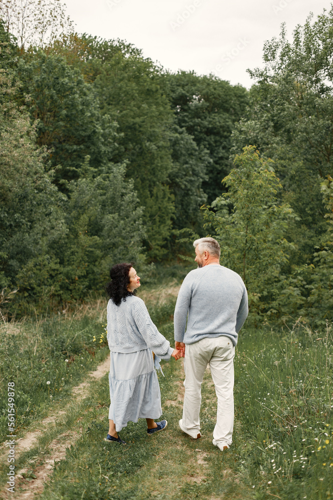 Senior couple holding hands and walking in a autumn park Senior couple holding hands and walking in a autumn park