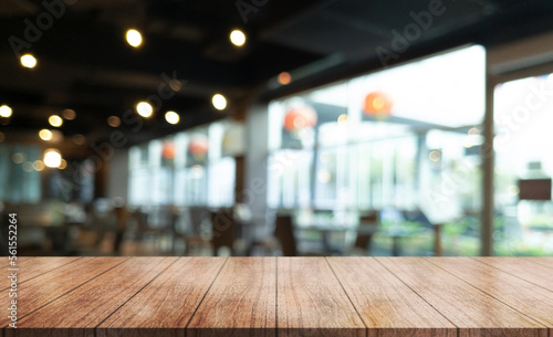 Empty wooden table top with lights bokeh on blur restaurant background.