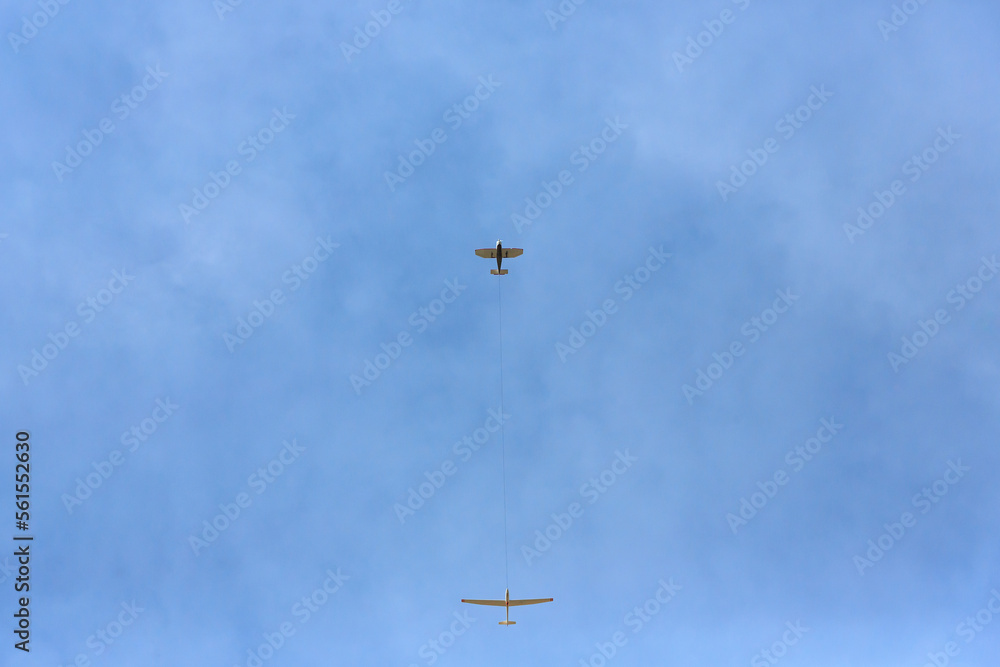A single-engine aircraft is towing a glider. Bottom view. A single-engine aircraft is towing a glider. Bottom view.