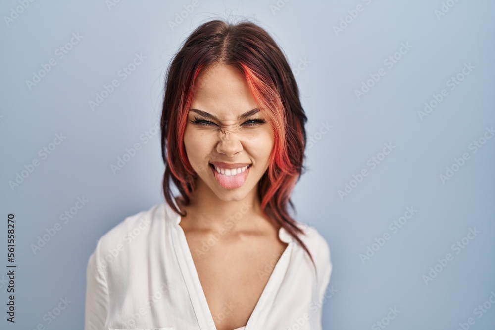 Young caucasian woman wearing casual white shirt over isolated background sticking tongue out happy with funny expression. emotion concept. Young caucasian woman wearing casual white shirt over isolated background sticking tongue out happy with funny expression. emotion concept.