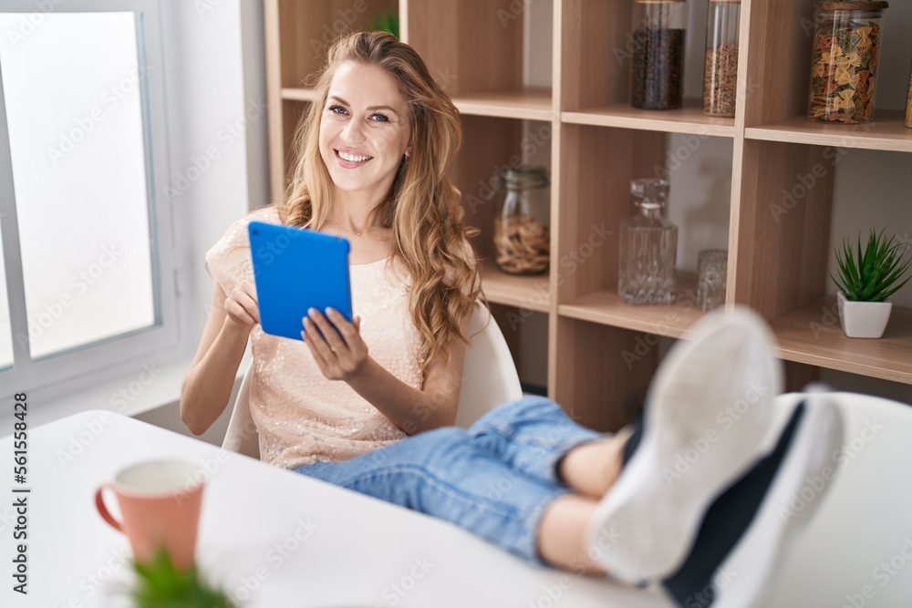 Young blonde woman using touchpad drinking coffee at home Young blonde woman using touchpad drinking coffee at home
