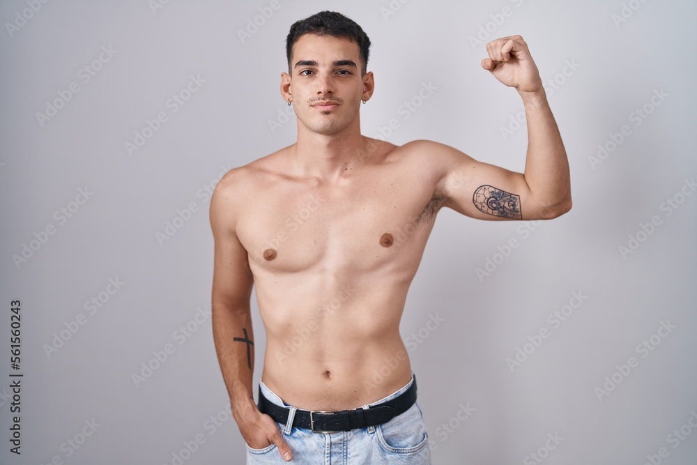 Handsome hispanic man standing shirtless strong person showing arm muscle, confident and proud of power