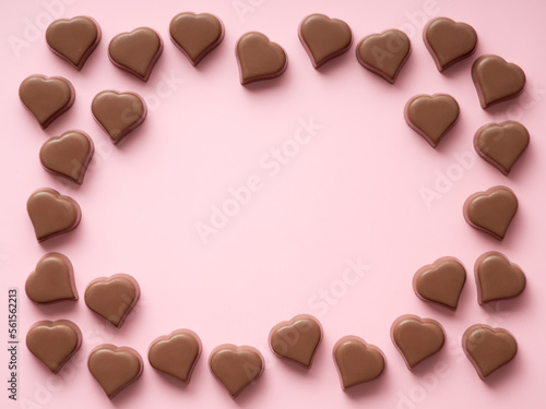 Frame of romantic chocolate confections in heart shapes on pastel pink background. Canvas with heart chocolate sweets with copy space. Valentines day background