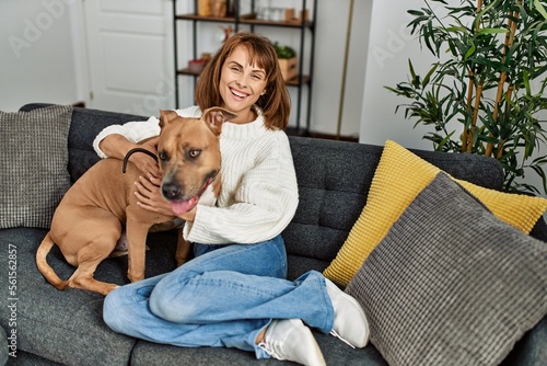 Young caucasian woman smiling confident hugging dog sitting on sofa at home