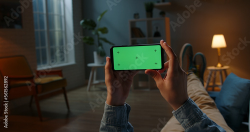 Close up shot of guy using his horizontal smart phone with mock up green screen at night, using various gestures while watching a video 